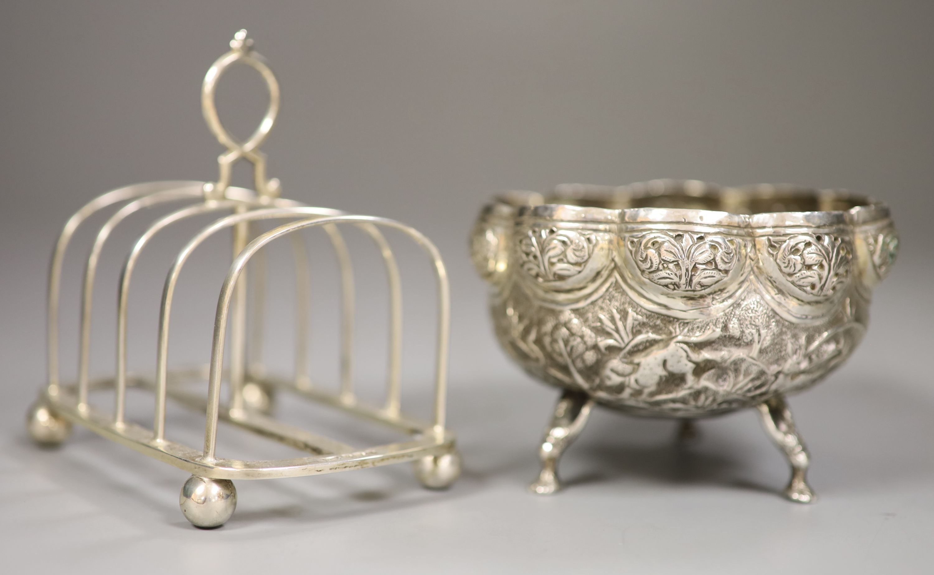 A George VI silver toastrack, Sheffield 1938, length 11.5cm and an Indian cusped white metal sugar bowl, 8oz.